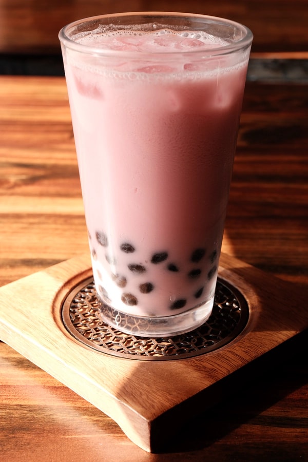 Colored boba milk tea on a wooden tray.