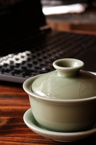 Closeup photo of a gaiwan in front of a laptop.